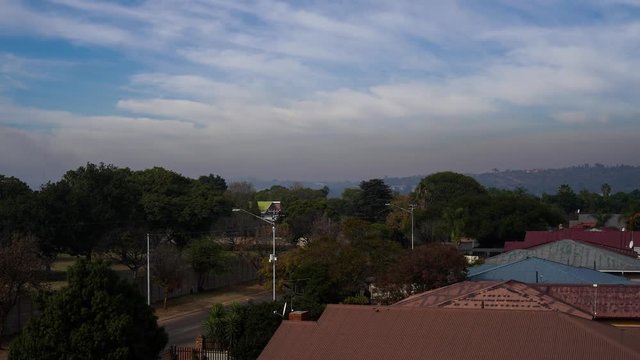 Timelapse of a suburb in Villieria, Pretoria, South Africa. Clouds moving on a sunny day. Rooftops and street in the foreground.