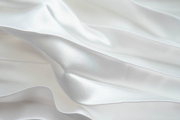 Fototapeta premium White luxury satin fabric folds background. Rippled white silk fabric satin cloth gathers glamour background. Smooth elegant white silk cloth texture can use for wedding backdrops. Retro style
