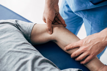 partial view of chiropractor massaging arm of patient in hospital