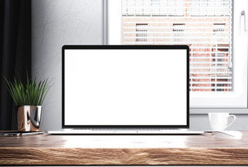 Laptop with blank screen on wooden desk in bright modern home interior