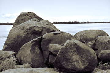 Fototapeta na wymiar Basalt boulders. Huge stones on the background of calm water. Sikachi Alyan. Close up.