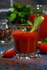 fresh tomato juice with salt and celery on dark table, vertical closeup