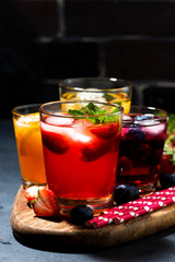 fruit and berry beverages with ice in assortment, vertical