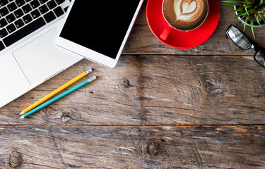office accessories laptop, tablet, pen, smartphone, notepad, and coffee cup on a wooden table background.Top view from above.