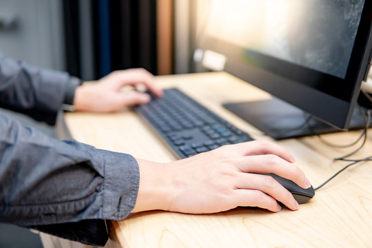 Male hand holding computer mouse while using desktop computer in furniture store. Interior material design simulation program for customer. Home improvement concept