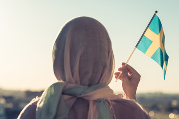 Muslim woman in scarf with Swedish  flag of at sunset.Concept