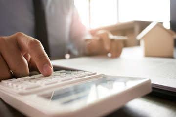 Real estate agent with house model and property documents to sale contract.