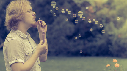 man blowing soap bubbles, having fun