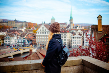 Young blonde tourist girl in warm hat and coat with backpack walking at cold autumn in Europe city enjoying her travel in Zurich Switzerland © Vasily Makarov