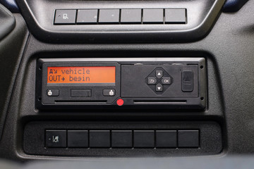 Digital tachograph display reads Vehicle Out Begin. No personal data. Tachograph in a van