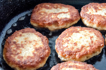Cutlets are roasted in an black frying pan.
