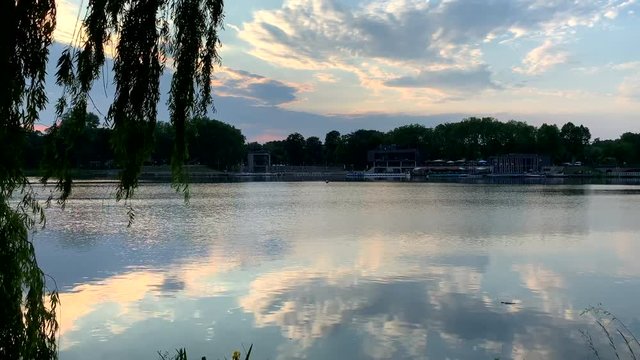 The sun is reflected in the clear blue water.  Beautiful lake and in the background you can see restaurants. Aasee Muenster, Germany.