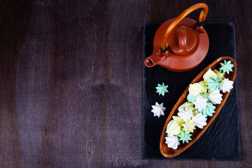 Meringue in a wooden bowl and and brown teapot