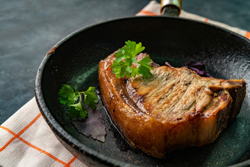 top view of a pork fried beef steak in a cast iron pen with herbs and spicess
