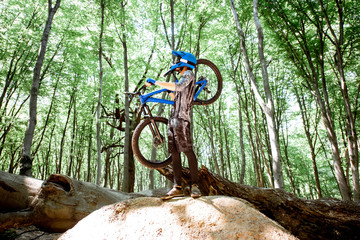 Fototapeta na wymiar Professional cyclist carrying bicycle while riding off road in the forest