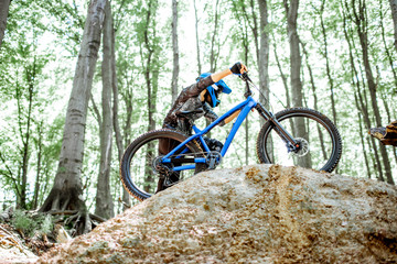 Professional cyclist carrying bicycle while riding off road in the forest. Concept of an extreme...