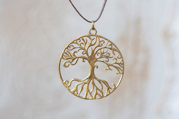 Brass metal tree shape pendant round mandala on neutral background