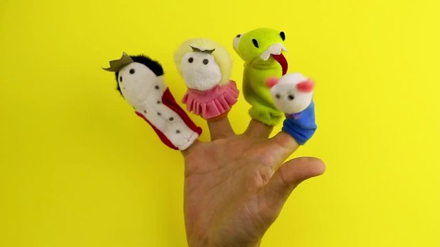 hand with finger puppet theatre,the dragon, prince,princess and king on a yellow background