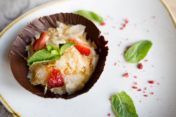 Sugar dessert with ice cream, strawberries and mint in chocolate plate. Tasty, delicious food