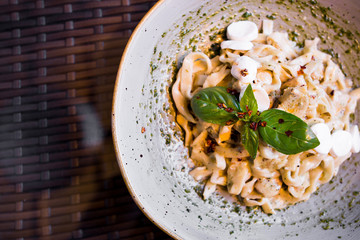 Traditional italian dish pasta with cheese mozarella, spices and green basil