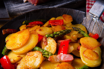 Fried potatoes with smoked bacon, green asparagus and paprika.