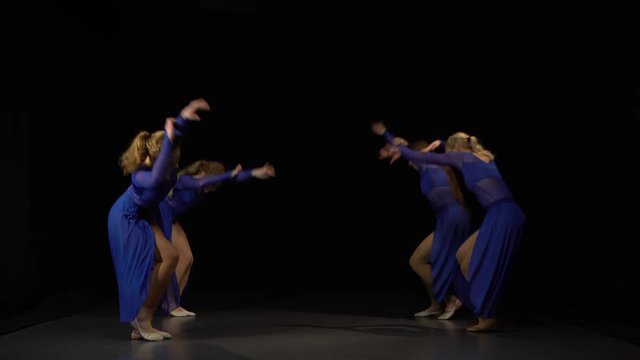 Flexible ballerinas are dancing on black background of studio.