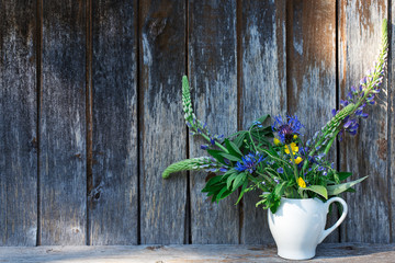 vase with wild flowers on the background of an old wooden wall