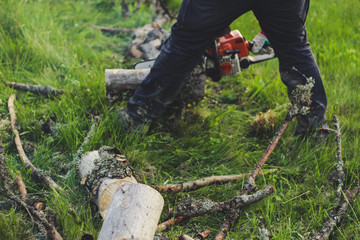 The guy chops the old tree in the mountains with a chainsaw. Ukrainian Carpathian Mountains. Bonfire. Tourism