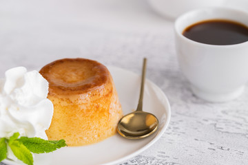 Creme caramel dessert or flan  decorated  with whipped cream and mint  and served with cup of coffee. Sweet moment background.
