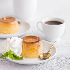 Creme caramel dessert or flan  decorated  with whipped cream and mint  and served with cup of coffee. Sweet moment background.