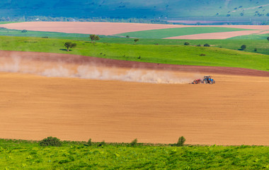 Dust from a tractor working in a field in spring