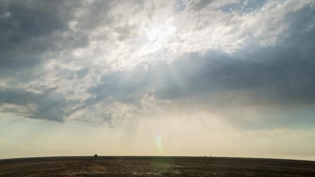 Time lapse of sun rays shining through the clouds moving over flat landscape in the Kansas plains.