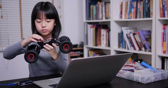 Little girl trying to fix robot in school alone. Giral having talent and she try to fix robot by herself. Technology and Education concept.