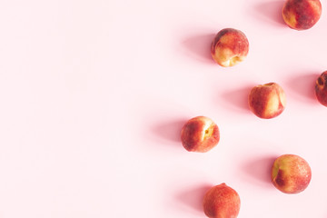 Peaches on pastel pink background. Frame made of fresh peaches. Flat lay, top view, copy space