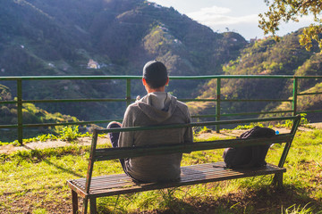 Tourist enjoying the view across Cinque Terre National Park and the morning sun, resting on a bench...