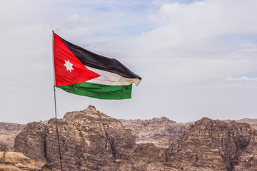 evolving on a wind Jordanian flag on a dry desert highland mountain unfocused nature background 