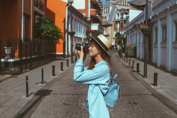 Photographer traveler in hat and with backpack takes pictures of sights while walking along the street of a european city. Vacation and travel holidays. Traveling lifestyle