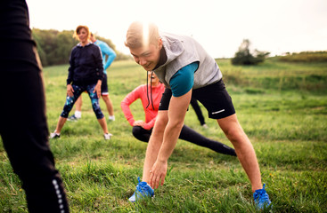 Large group of fit and active people doing exercise in nature.