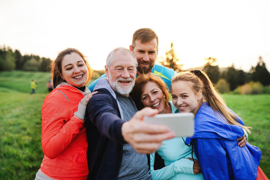 A group of fit and active people resting after doing exercise in nature, taking selfie.