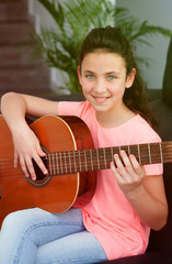 Young girl playing guitar at home