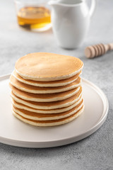 Pancakes stack with butter and honey. Grey backround.