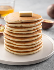 Pancakes stack with butter and honey. Grey backround.
