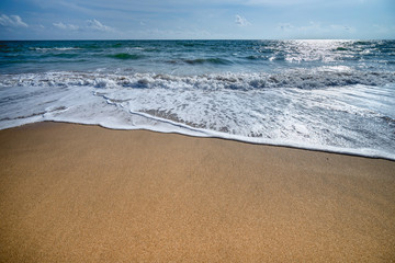 The beautiful waves of blue ocean on the fine sand beach on a sunny day.