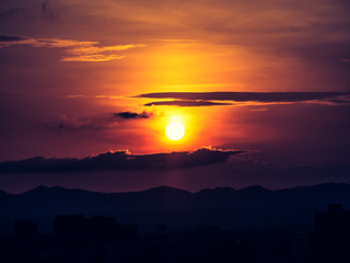 Obraz premium The orange sun and dark clouds over the city.