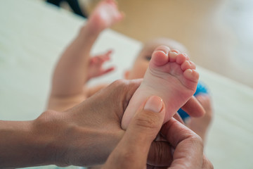 Close-up of a small child's legs in female hands. Parental care of children. The concept of family