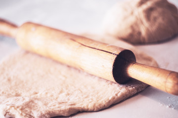 Classic wooden rolling pin with freshly prepared dough and dusting of flour on white background
