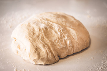 Classic wooden rolling pin with freshly prepared dough and dusting of flour on white background