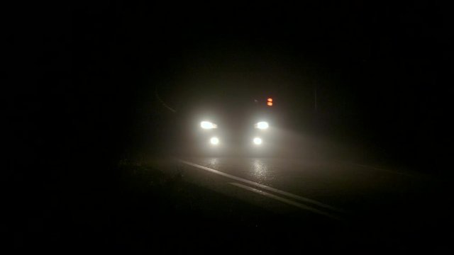 Car headlights of auto driving in thick fog on the road at night in Torrevieja, Spain. 4K