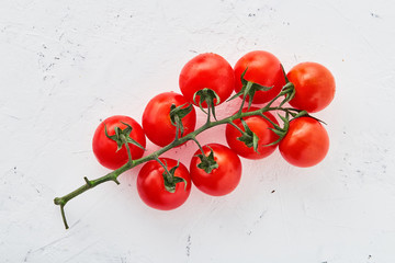 Cherry tomatoes on white textured background. Cherry tomatoes on a branch. Composition of cherry tomatoes