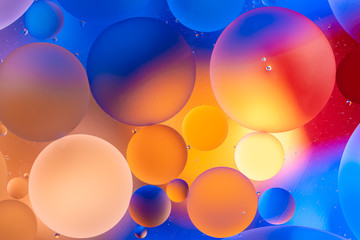 bright yellow and blue oily drops in water with colorful background, close-up 